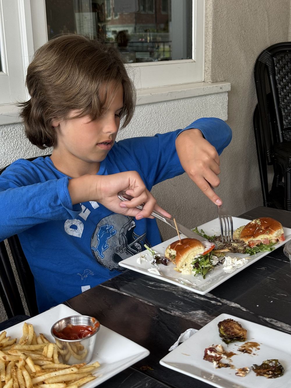 Kid cutting the burger with fork and knife