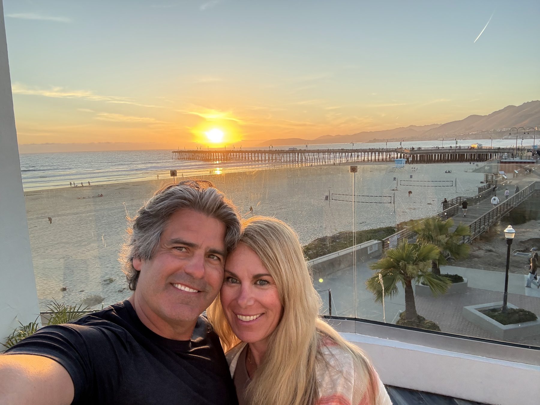 Jay and Dana on the hotel balcony with the beach and pier behind them