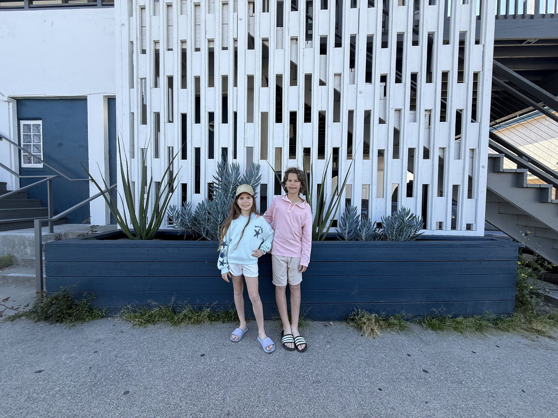 Three kids posing by the Sandcastle Hotel on the Beach sign