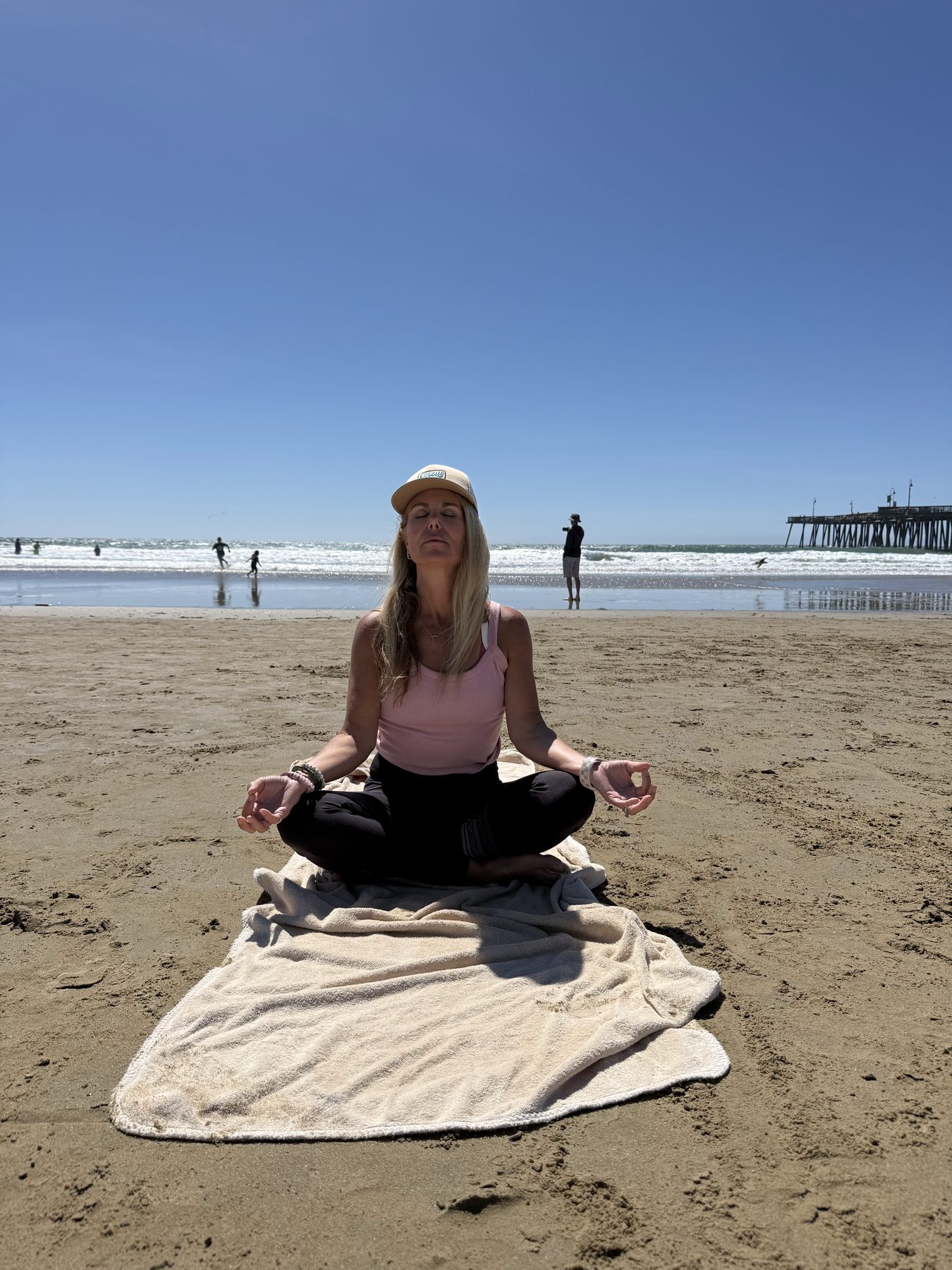 Dana in lotus pose meditating on the beach