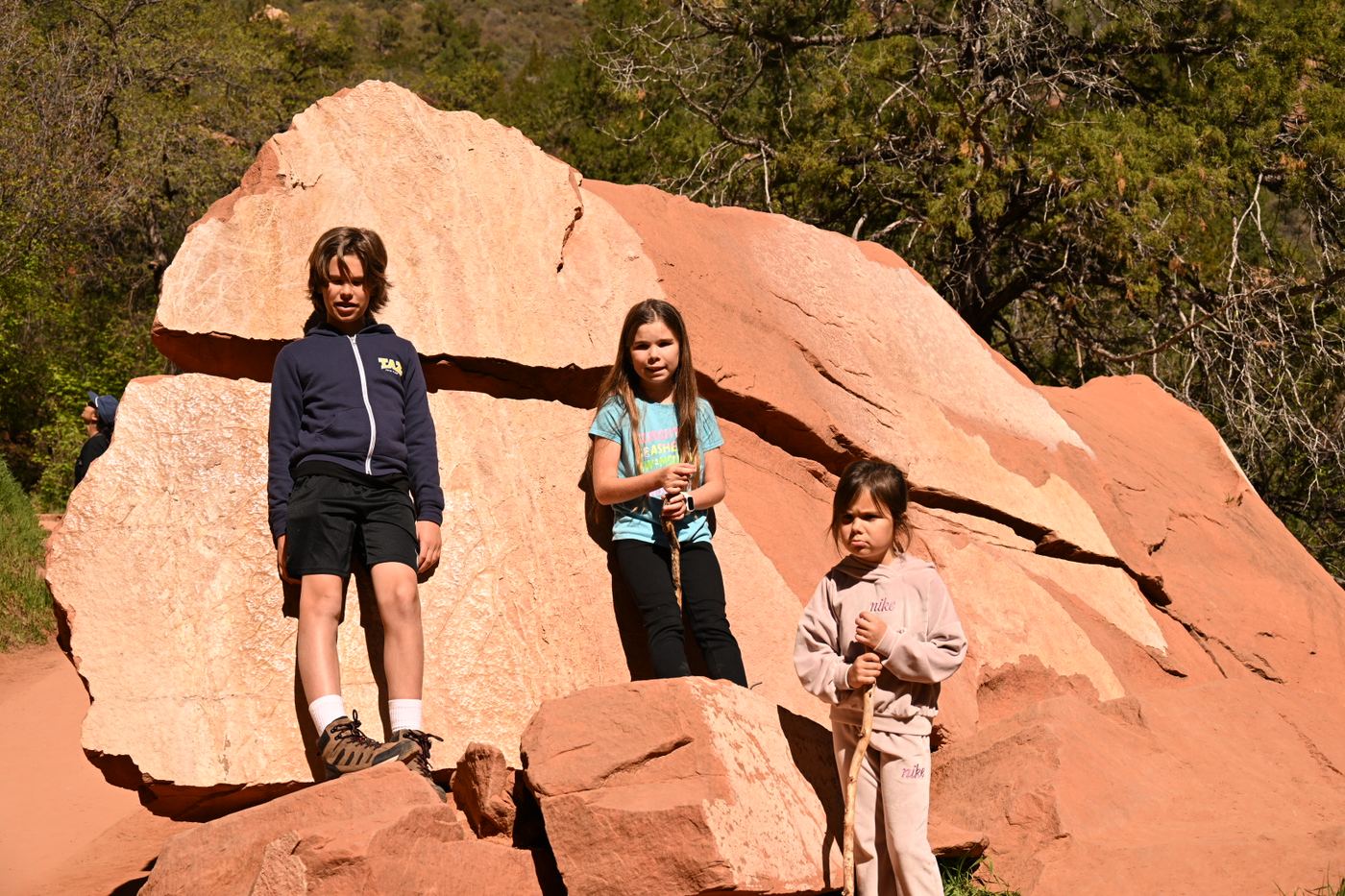 Three kids on a big red boulder